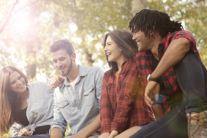 Young people sitting outside smiling