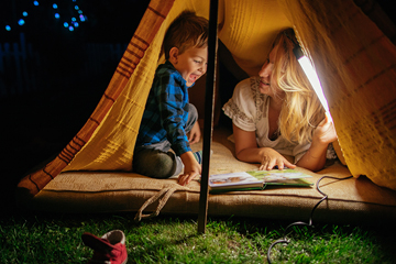 mother and child under a tent at night reading