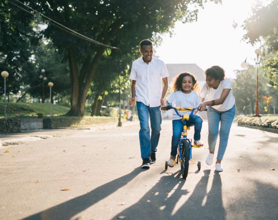 parents teaching child to ride bike
