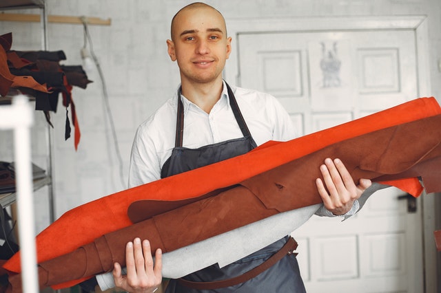 shop owner in black apron holding product for sale