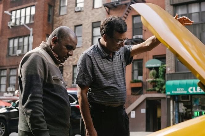 two men looking into a car engine