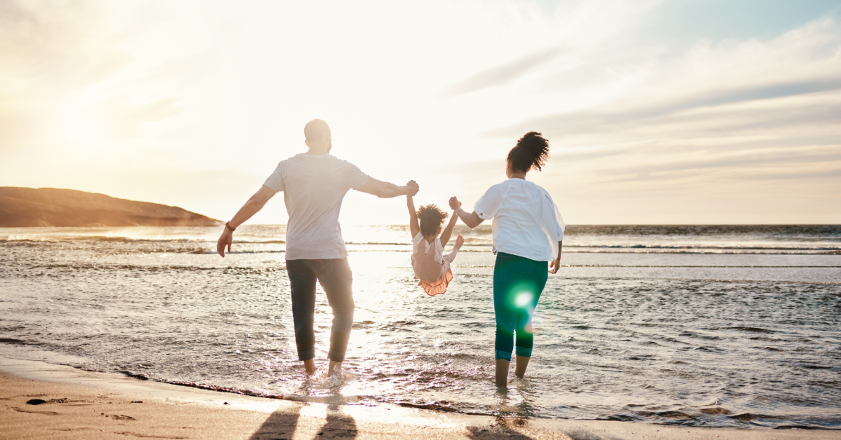 man and woman holding child in the ocean