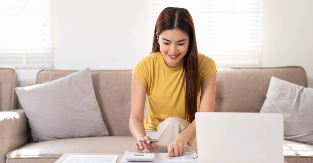 Asian woman checking finances using calculator and laptop